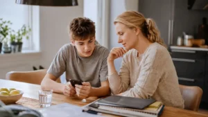 Jugendlicher prüft mit einem Elternteil Konto und Smartphone